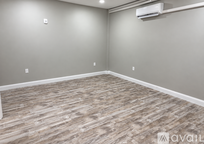A room with a wooden floor and an air conditioner on the wall.