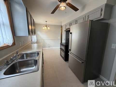 A kitchen with a black refrigerator and a silver sink.
