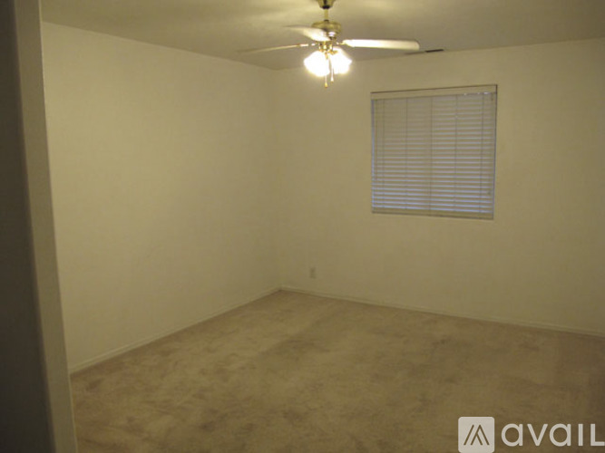 A room with a ceiling fan and a window with blinds.