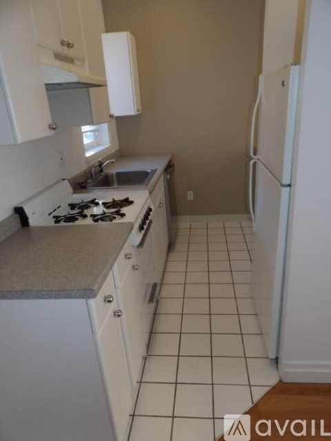 A kitchen with white cabinets and a white fridge.