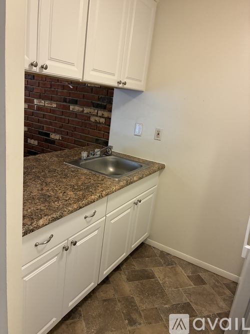 A kitchen with white cabinets and a granite countertop.