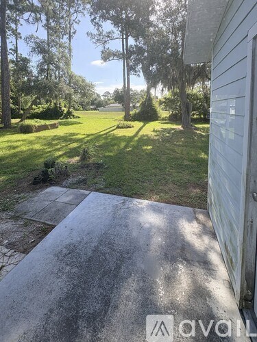 A concrete pathway leads to a grassy area with trees in the background.