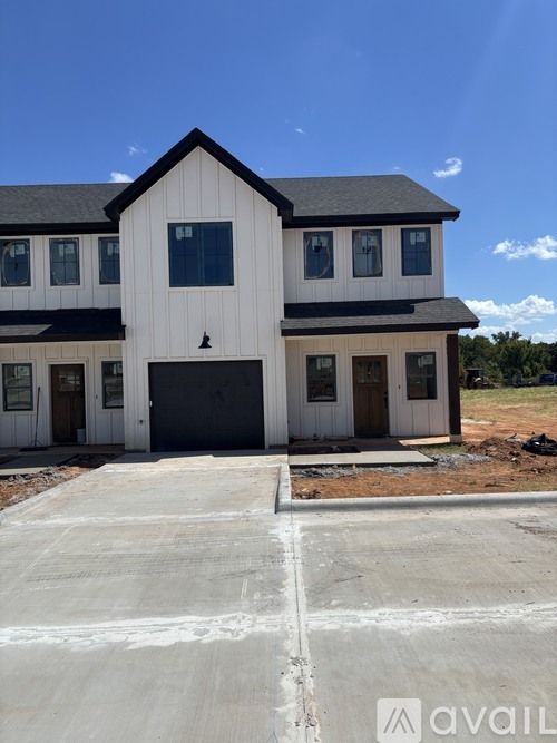 A large white house with a black roof and a garage door.