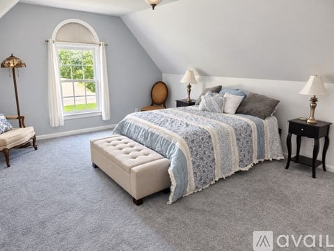 A bedroom with a large bed and a window with a view of a lawn.