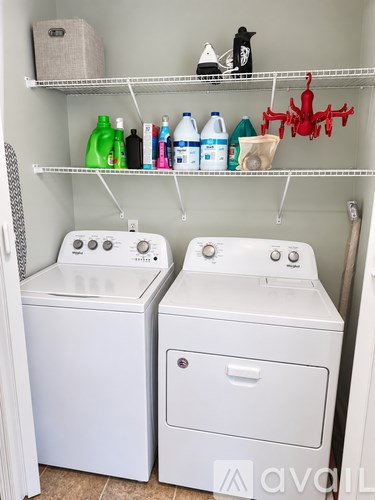 A laundry room with two washing machines and a shelf with various items on it.