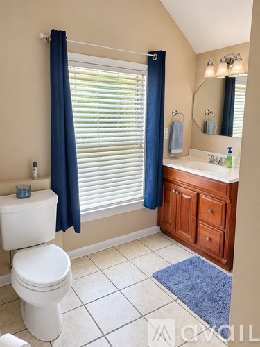 A white toilet with a blue towel and a blue rug in a bathroom.