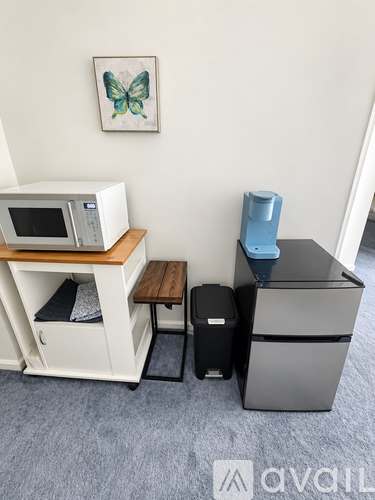 A kitchen with a microwave on a shelf and a refrigerator.