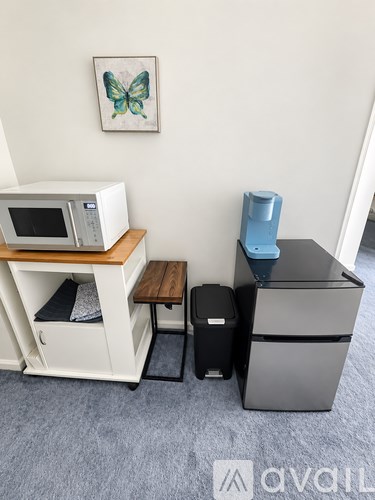 A kitchen with a microwave on a shelf and a refrigerator.