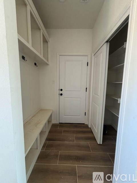 A kitchen pantry with a white door and a bench.