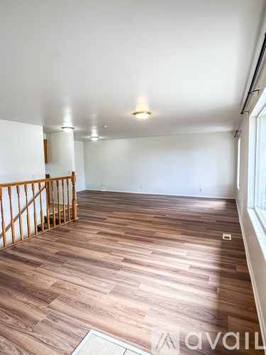 A room with wooden flooring and a window on the right side.