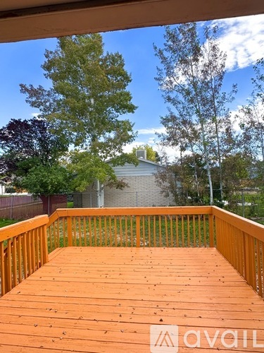 A wooden deck with a railing and trees in the background.