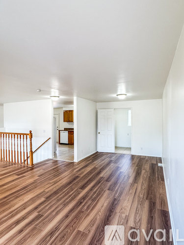 A spacious room with wooden flooring and white walls.