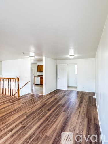 A spacious room with wooden flooring and white walls.