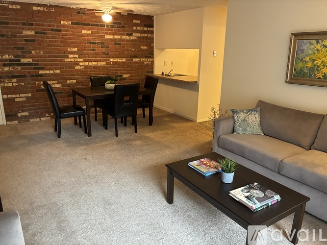 A living room with a grey couch, a black coffee table, and a brick wall.