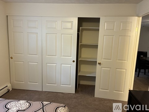 A room with a carpeted floor and a wall of white doors.