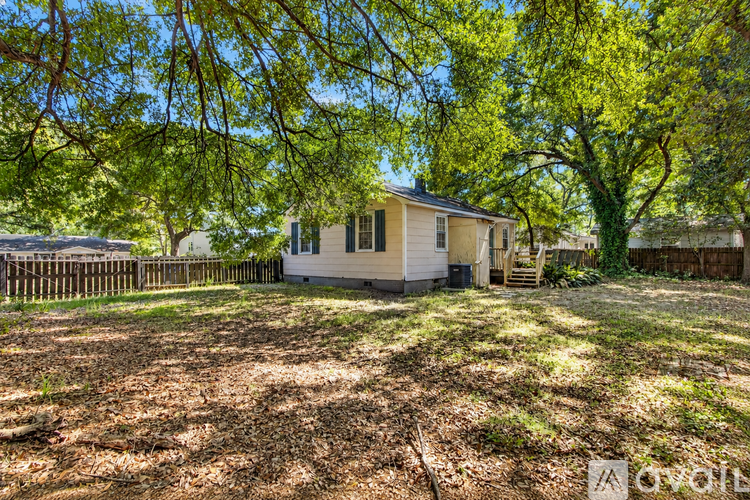 A house is surrounded by trees and has a fence in front of it.