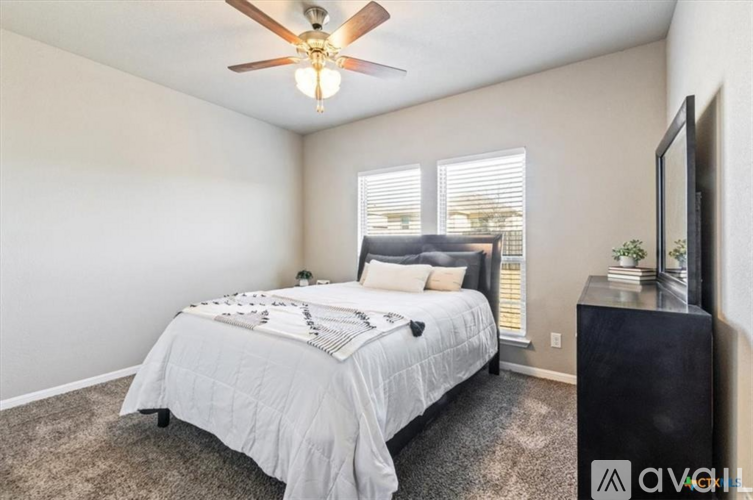 A bedroom with a bed, a ceiling fan, and a television.
