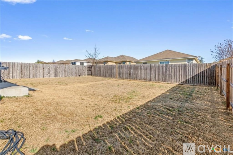 A backyard with a wooden fence and a grassy area.