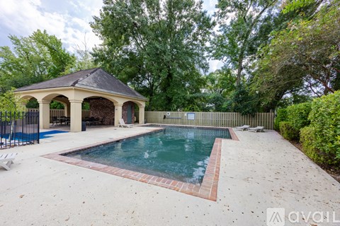 A backyard with a pool and pavilion.