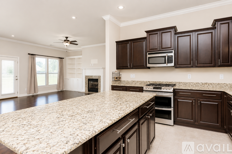 A kitchen with dark brown cabinets and a granite countertop.