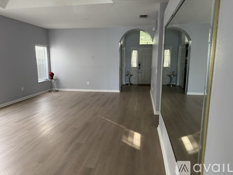 A spacious room with wooden flooring and white walls.