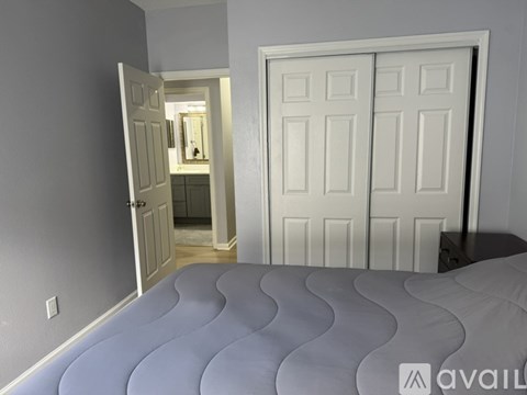 A bedroom with a large bed and two doors.