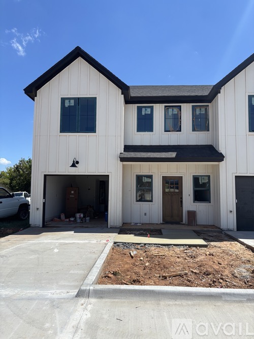 A white two-story house with a garage and a driveway.