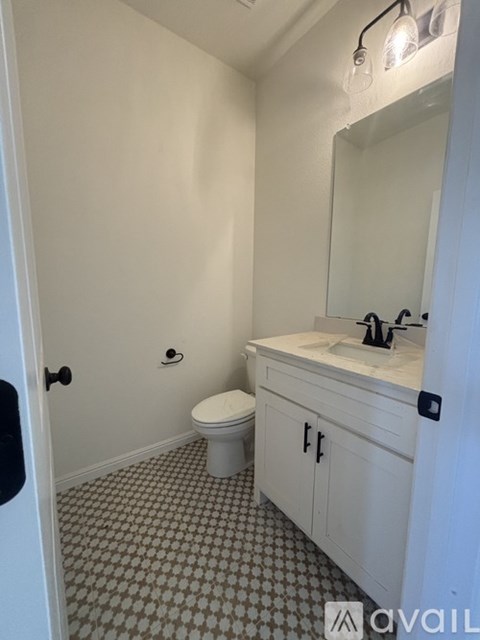 A bathroom with a toilet, sink, and mirror.