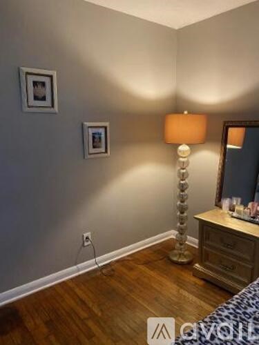 A bedroom with a bed, dresser, and lamp.
