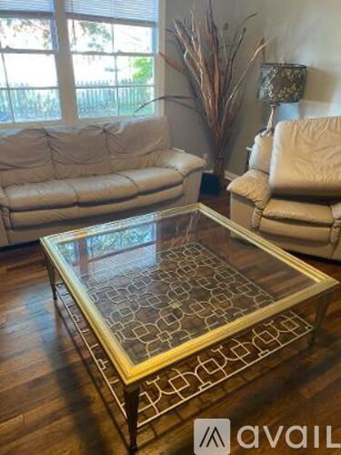 A living room with a glass coffee table and two couches.
