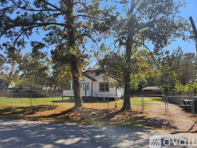 A house is surrounded by a fence and trees.