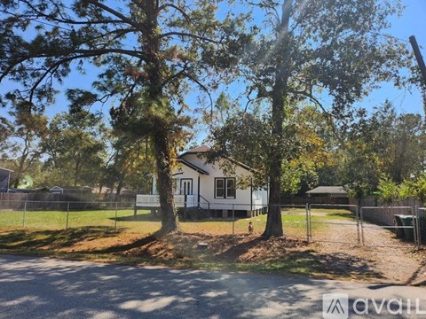 A house is surrounded by a fence and trees.