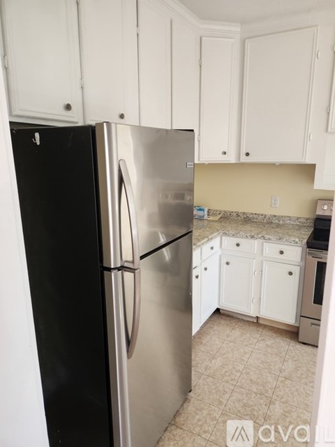 A kitchen with a black refrigerator and a stainless steel refrigerator freezer.