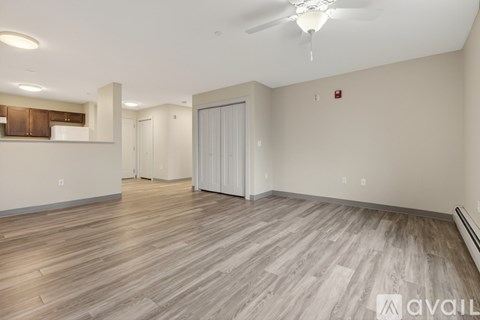 A spacious room with wood flooring and a ceiling fan.