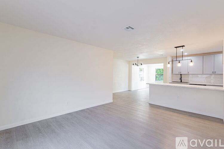 A spacious room with a long white wall and a wooden floor.