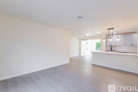 A spacious room with a long white wall and a wooden floor.