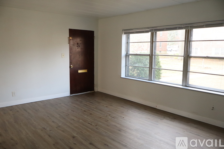 A room with a brown door and a window overlooking a street.