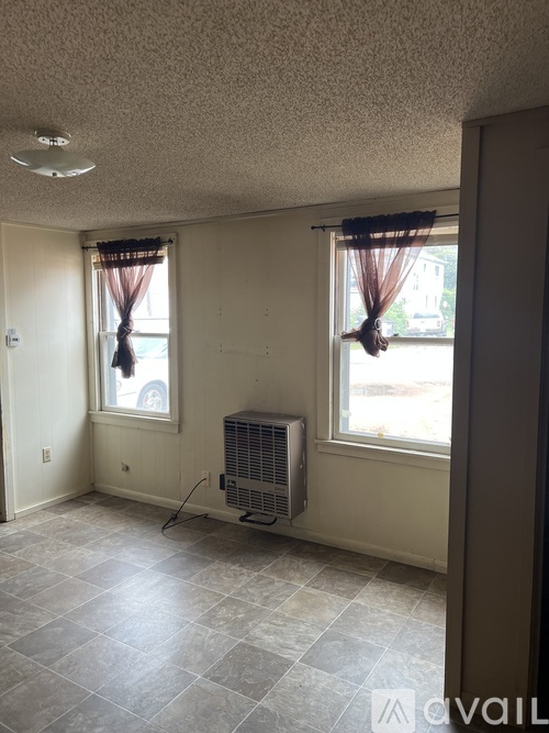 A room with a tile floor, a window with curtains, and a wall-mounted air conditioner unit.