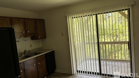 A kitchen with a black refrigerator and wooden cabinets.