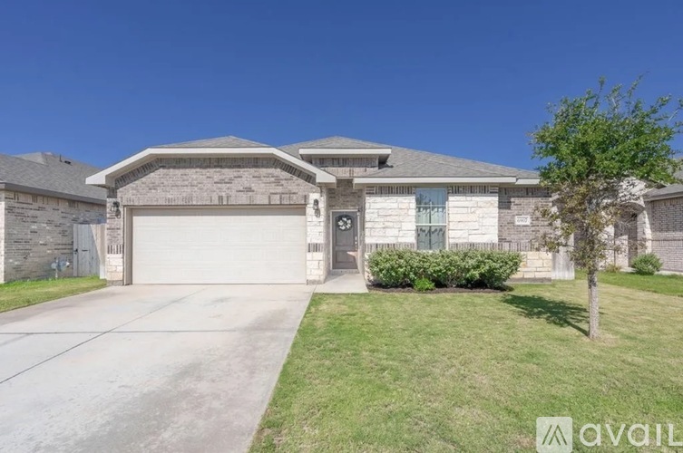 A house with a garage and a tree in front.