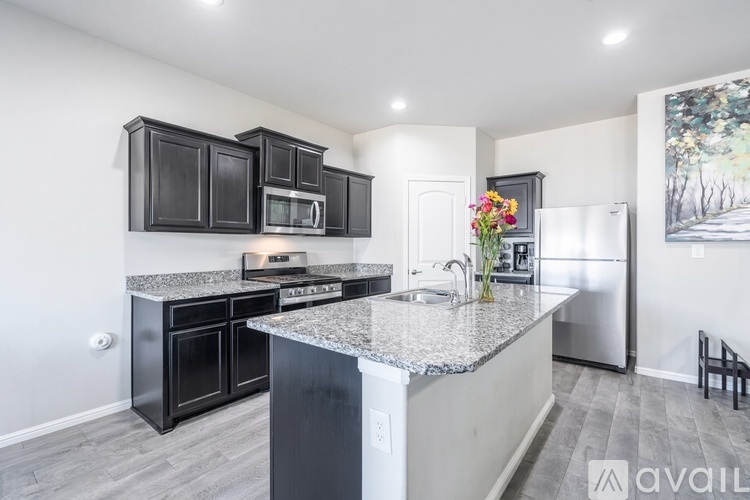 A kitchen with black cabinets and a granite countertop.