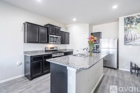 A kitchen with black cabinets and a granite countertop.