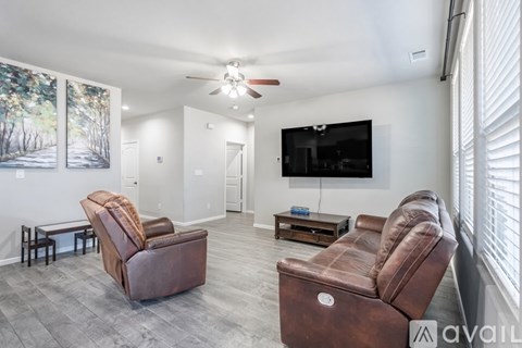 A living room with a brown leather chair and a flat screen TV mounted on the wall.