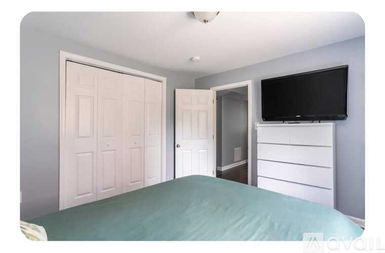 A bedroom with a bed, a television, and two doors.