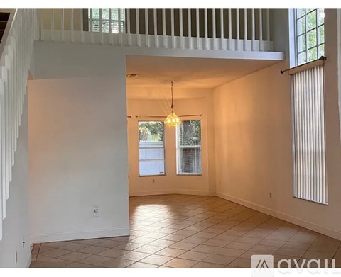 A spacious room with a tiled floor and a staircase on the left side.