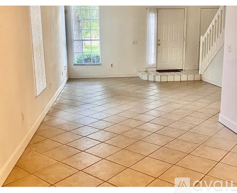 A spacious room with tiled flooring and a staircase on the right.