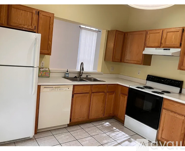A kitchen with white appliances and wooden cabinets.