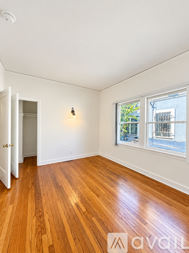 A room with wooden floors and a window showing a view of a building outside.