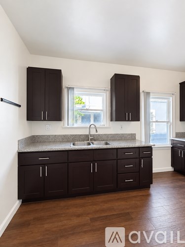 A kitchen with dark brown cabinets and a granite countertop.