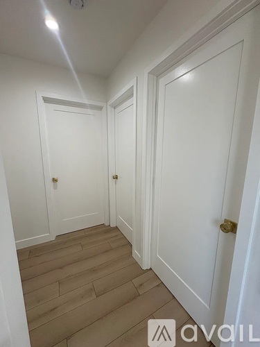 A hallway with white doors and wooden floors.